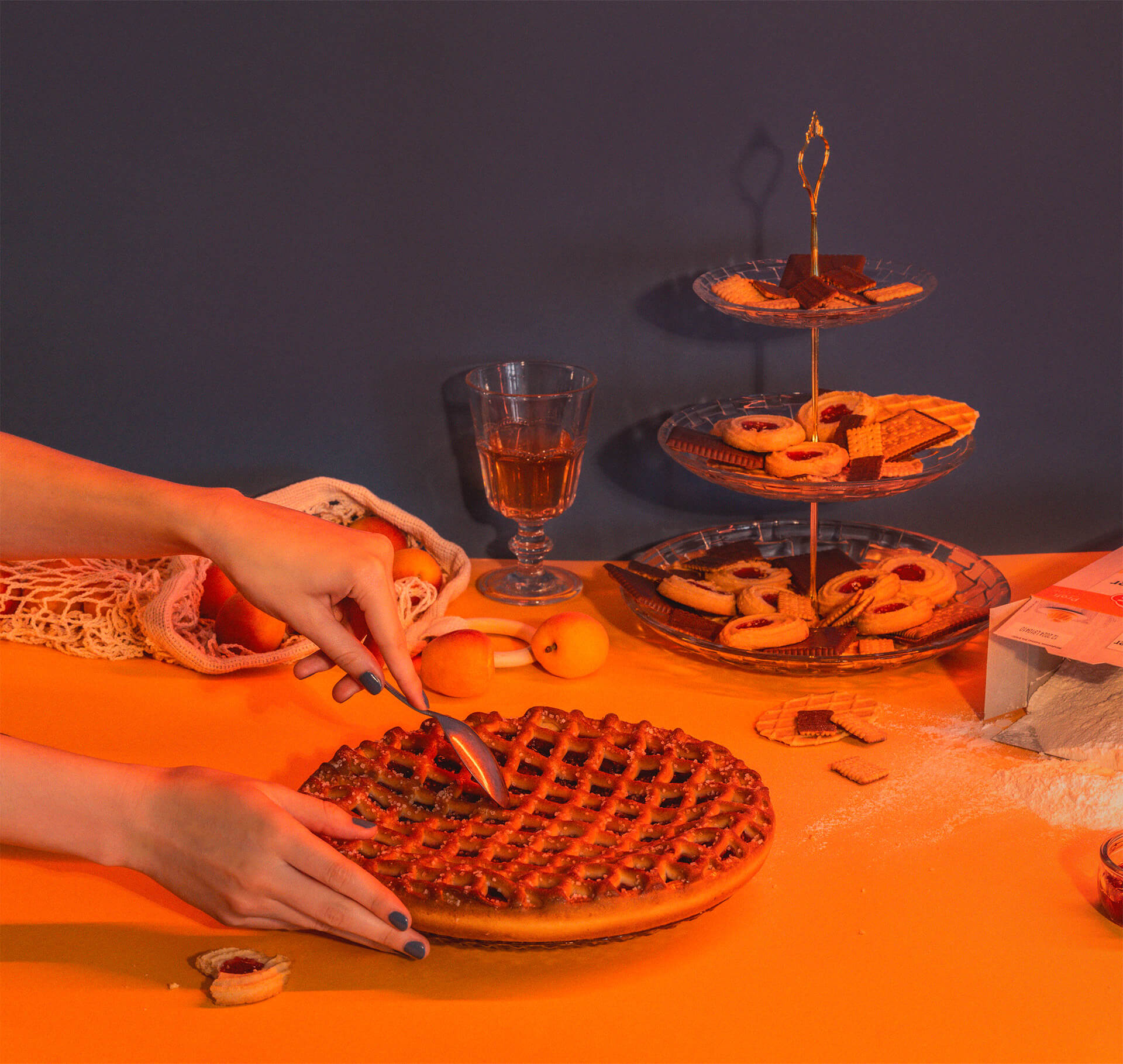 Stillleben in Orange, zwei Hände schneiden eine Tarte neben einer Etagere