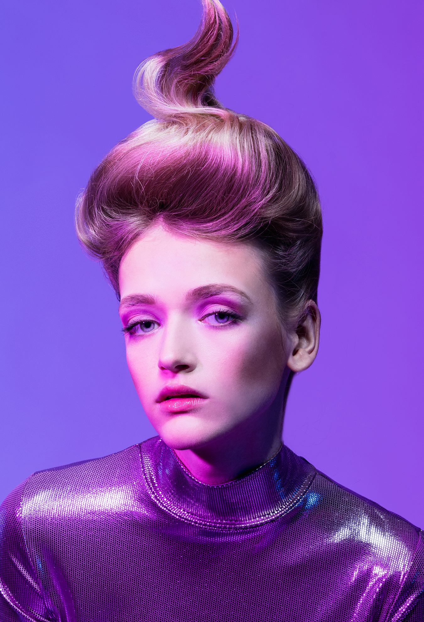 Beauty-Editorial in Violett, Frau mit hochgestecktem Haar und metallischem Rollkragen